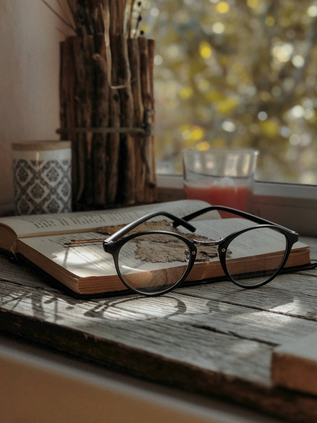 Occhiali da lettura appoggiati su un libro aperto su un tavolo di legno.